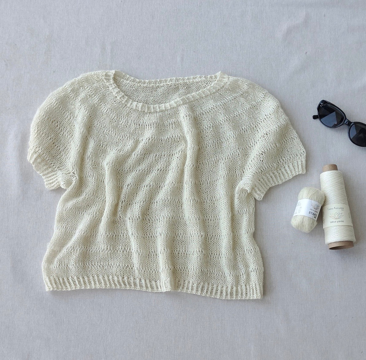 Ecru summer tee knitted in Lotus Yarns Stars, laid flat with the yarn
