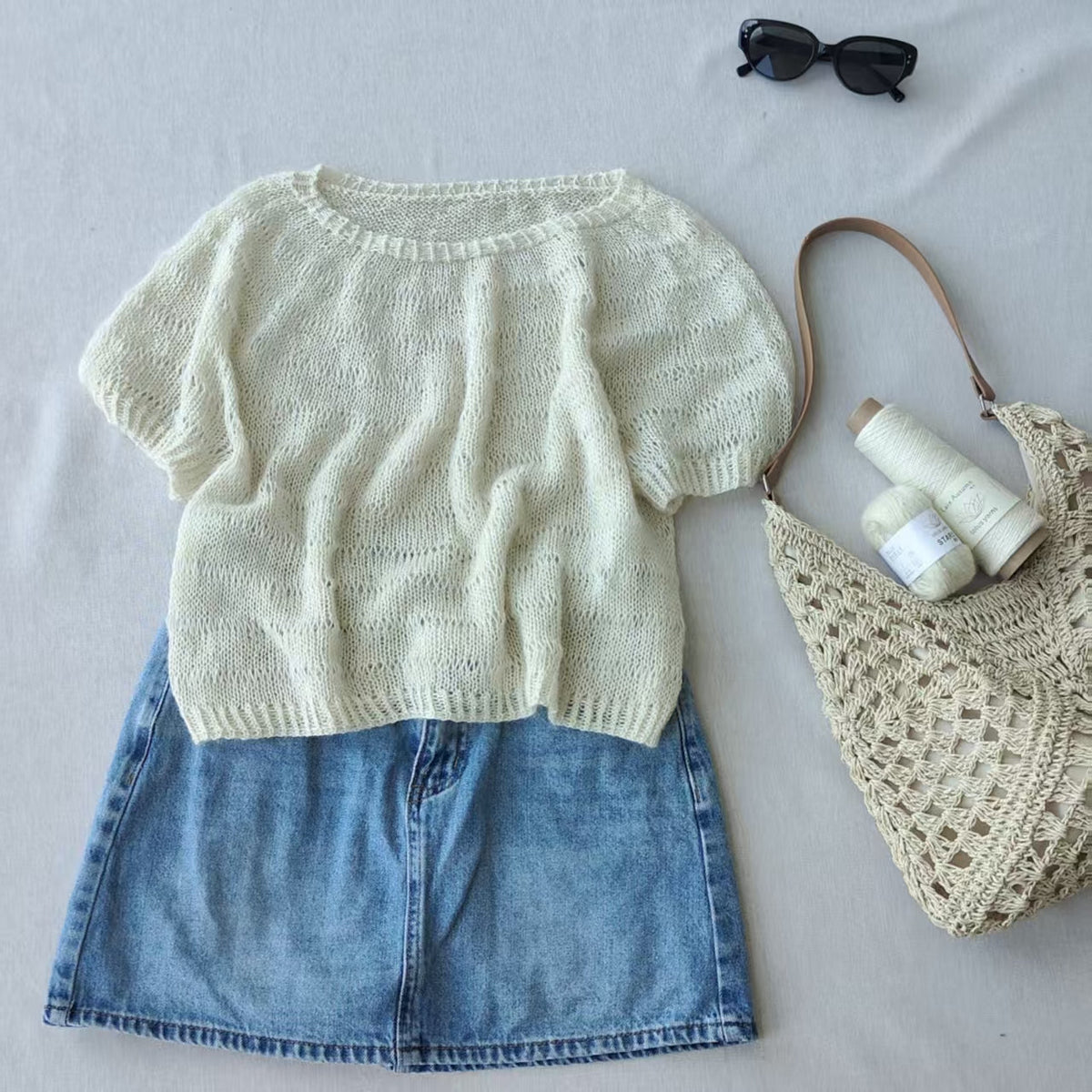 Stars top laid flat with a denim skirt and a crochet bag